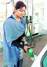 A girl fills a tank at a petrol station on the outskirts of Jammu on Monday.