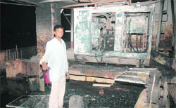 An employee of the furniture showroom shows the damaged generator on the roof in Industrial Area, Phase II, Ram Darbar, on Wednesday.