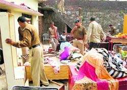Policemen attach the property of a murder accused in Dehradun on Wednesday