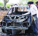 Policemen investigate the car in which a 56-year-old businessman was found charred near TV Tower, Pitam Pura in New Delhi