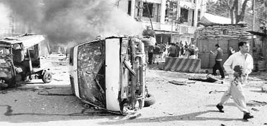 An injured man walks past a burning vehicle at the blast site in Saidu Sharif area of Swat valley