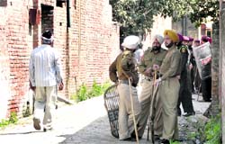 Police personnel guard the lanes of the village after a communal clash. Tribune photos: Himanshu Mahajan