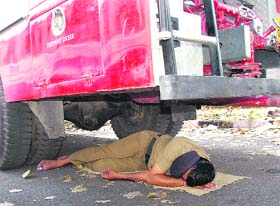 A firefighter takes a nap under a fire engine in Chandigarh on Tuesday.