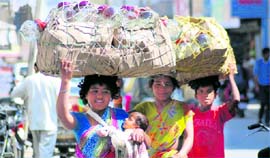 A woman with a child and others sell crockery items in Karnal.