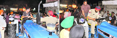 A cop asks for documents from the youth; and (right) the tractor being impounded in Model Town in Ludhiana.