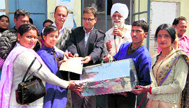 Sant Nirankari Mandal Zonal in charge Harbhajan Singh and OP Uniyal present a sewing machine to a student in Mussoorie on Friday.