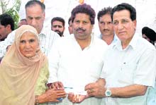 Revenue Minister Raman Bhalla gives a compensation cheque to a woman, who had migrated from Pakistan in 1947, in RS Pura on Friday. 