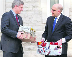 Canada's PM Stephen Harper (L) is presented with two cases of beer by US Ambassador to Canada David Jacobson in Ottawa on Friday after US President Barack Obama lost a bet with Harper on the outcome of the Olympic men's ice hockey gold medal game between Canada and the US.