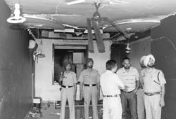 Policemen inspect the damaged building and goods after a blast at an office in Zirakpur
