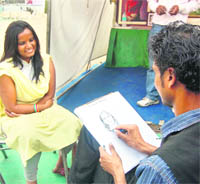 An artist makes a sketch of a girl at the Gandhi Shilpkar Mela in Dehradun on Monday.