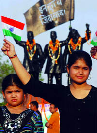 Children wave the national flag on Martyrs Day at Shahidi Park in New Delhi on Tuesday.