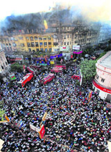 People crowd a road as fire personnel try to douse a major fire that broke out in a multi-storey building at Park Street in Kolkata on Tuesday.