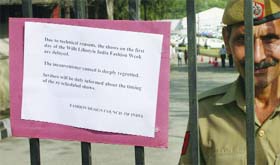 A policeman stands beside the notice on the entry gate of the fashion week venue in New Delhi