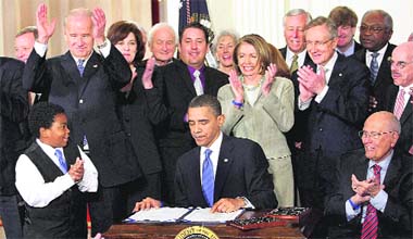 President Barack Obama signs the health care bill amid applause in the East Room of the White House in Washington