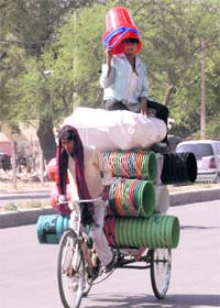 A man sitting atop a rickshaw uses buckets to protect himself from the scorching sun in Gurgaon