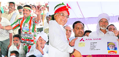 Chief Minister Bhupinder Singh Hooda gives a biometric card to a pensioner; and (L) a Congress supporter at the Vikas Rally in Assandh in Karnal