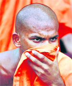 A student Buddhist monk covers his face after clashing with police during a protest in Colombo on Friday.