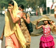 A little girl covers her head with her mothers dupatta 