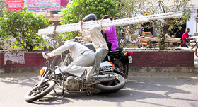 A motor cyclist and his pillon rider, dangerously holding pipes, fall on another two-wheeler on the Rajpur Road in Dehradun on Friday.