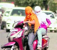 Girls cover their faces to beat the heat in Gurgaon on Saturday. Tribune photo: Sayeed Ahmed