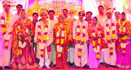 Brides and bridegrooms pose during a mass marriage ceremony organised by the Palki Sewa Samiti at Adarsh Nagar in New Delhi on Sunday.