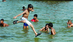 Children play at the India Gate watercourse to beat the rising temperature of the Capital on Sunday. 