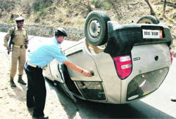 A policemen examines a car which overturned on the Jammu-Srinagar national highway