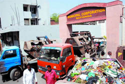 Municipal staff block the main gate of the BMC office with garbage-laden vehicles to register their protest, in Bathinda on Wednesday