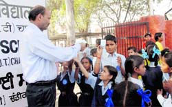 A uniform vendor distributes his visiting cards outside government school at Kajheri village. Tribune photo: Manoj Mahajan