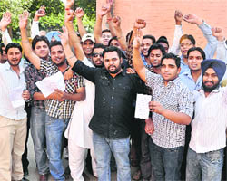 Students raise slogans against the PU authorities for setting an out-of-syllabus question paper.