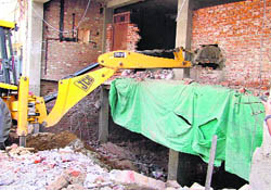 Pillars and beams constructed illegally being demolished by a JCB machine at the Nim Wali Street in Ludhiana on Wednesday.
