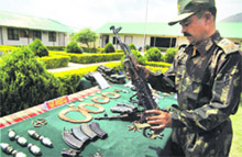 An Army man in Reasi displays arms and ammunition seized from Lashkar-e-Toiba militants killed in an encounter in Rajouri on Friday.