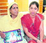 Amarjeet Kaur and Harmandeep Kaur, mother and sister of Navjot Singh, show his photograph. 