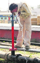 As the temperature rises, a man quenches his thirst at a railway water supply pipe in Amritsar on Saturday.