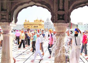 A sewadar pours water on marble structures around the Golden Temple for respite from the scorching heat, in Amritsar on Sunday.