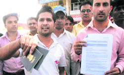 Disgruntled people show their documents and passports outside the office of Healthyway Immigration Consultants Private Limited at Sector 42 in Chandigarh 
