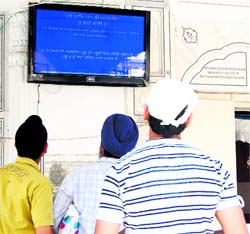 Devotees read information on an LCD television put up in the Golden Temple complex. A Tribune photograph