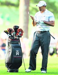 Tiger Woods waits alongside his golf bag during a practice round prior to the 2010 Masters Tournament at Augusta National Golf Club