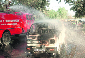 Firemen sprinkle water on a Maruti van that caught fire due to an apparent short-circuit in the engine, at Sector 34, Chandigarh, on Tuesday.
