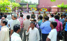 People stand outside the Jeewan Bharti building as it was evacuated after a hoax bomb call, in New Delhi on Tuesday.