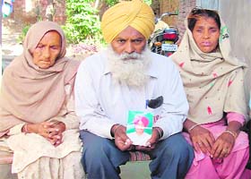 Harbans Singh shows a photograph of his son Satnam