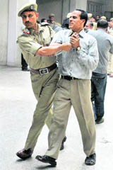 A policeman takes a striking government employee into preventive custody from the GMCH in Jammu on Wednesday.