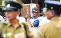 A Sri Lankan election worker carrying a ballot box walks past security personnel in Colombo on Wednesday. 