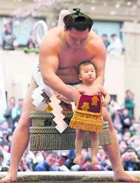 Sumo grand champion Yokozuna Hakuho of Mongolia holds up Aiki, son of sumo wrestler Kotomitsuki, during an annual sumo tournament in Tokyo