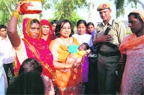 Additional Deputy Commissioner Pankaj Chaudhary, who holds the child, accompanies women towards a well for Kuan Poojan at Kariwala village in Sirsa