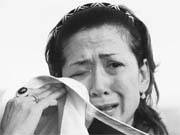 An anti-government Red Shirt protester wipes her face after tear gas was fired during clashes in central Bangkok on Saturday.