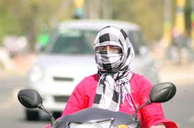 A girl covers her face with a scarf to protect herself from the scorching heat in Gurgaon
