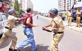 Security personnel cane charge a man during the municipal corporation elections in Navi Mumbai on Sunday