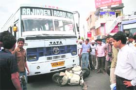People gather around a bus that hit a scooterist at Bikram Chowk in Jammu
