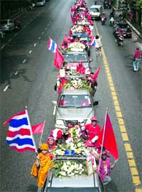 Anti-government "red shirt" demonstrators lead a procession with flag-draped coffins through the 